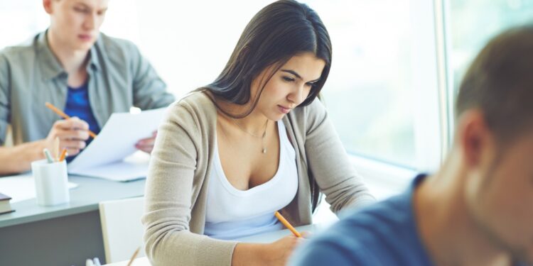 Estudantes realizando prova ou atividade em sala de aula.