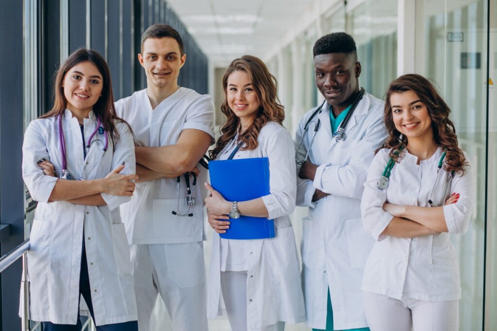 Grupo de profissionais da saúde sorrindo em um corredor de hospital.