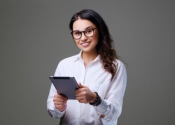 Mulher sorridente segurando um tablet, representando uma carreira promissora.