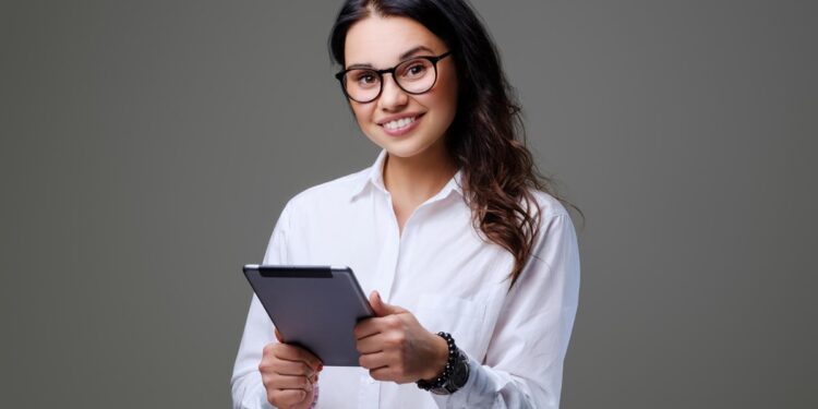 Mulher sorridente segurando um tablet, representando uma carreira promissora.