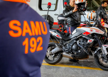 Profissionais do SAMU se preparam para uma emergência, ao lado de motos de resgate.
