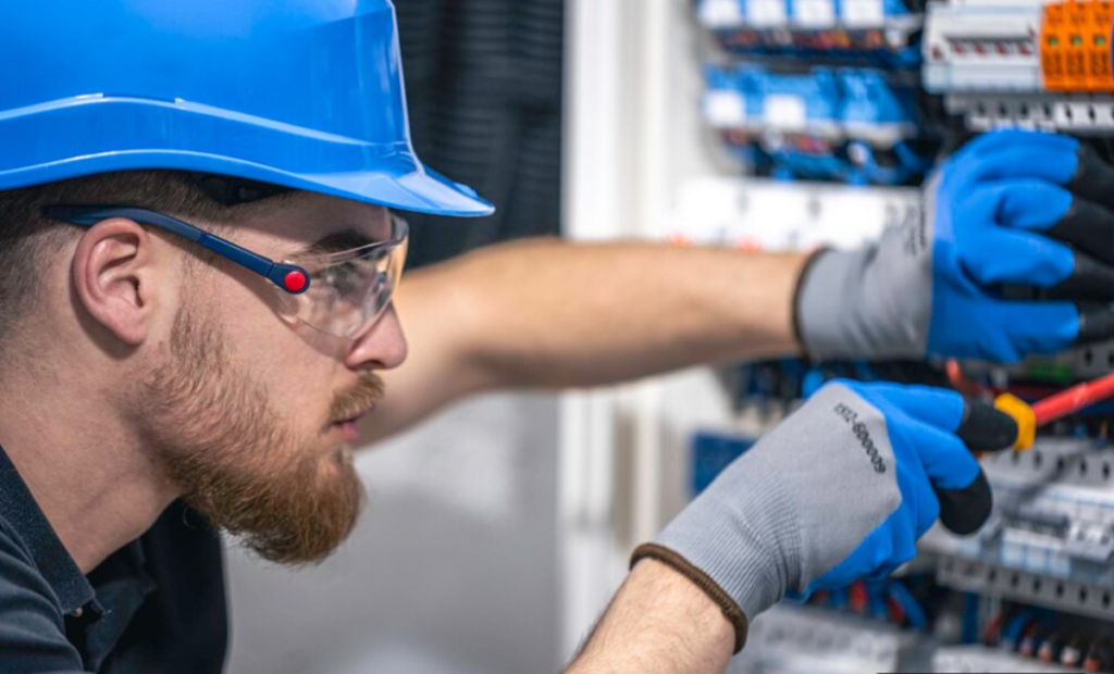 Técnico em eletrotécnica realizando manutenção e ajustes em painéis elétricos.