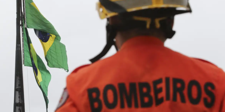 Bombeiro observa a bandeira do Brasil, representando o concurso CBMERJ