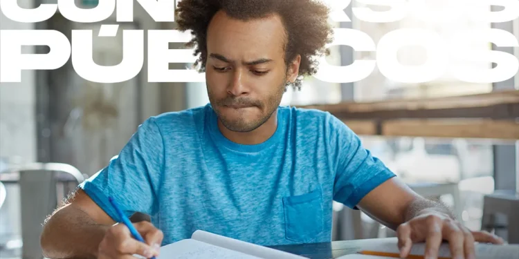 Candidato focado estudando para concurso público, com materiais de estudo sobre a mesa