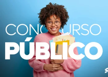 Mulher sorrindo com óculos e cabelo cacheado segurando materiais de estudo para concurso público