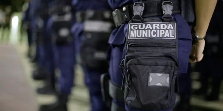 Uniforme da Guarda Municipal com destaque para bolsa tática e emblema, representando a corporação