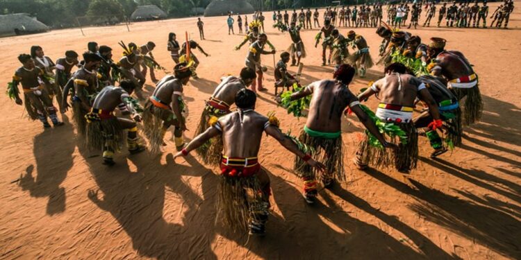 Indígenas em dança tradicional em comunidade, representando a cultura protegida pela FUNAI.