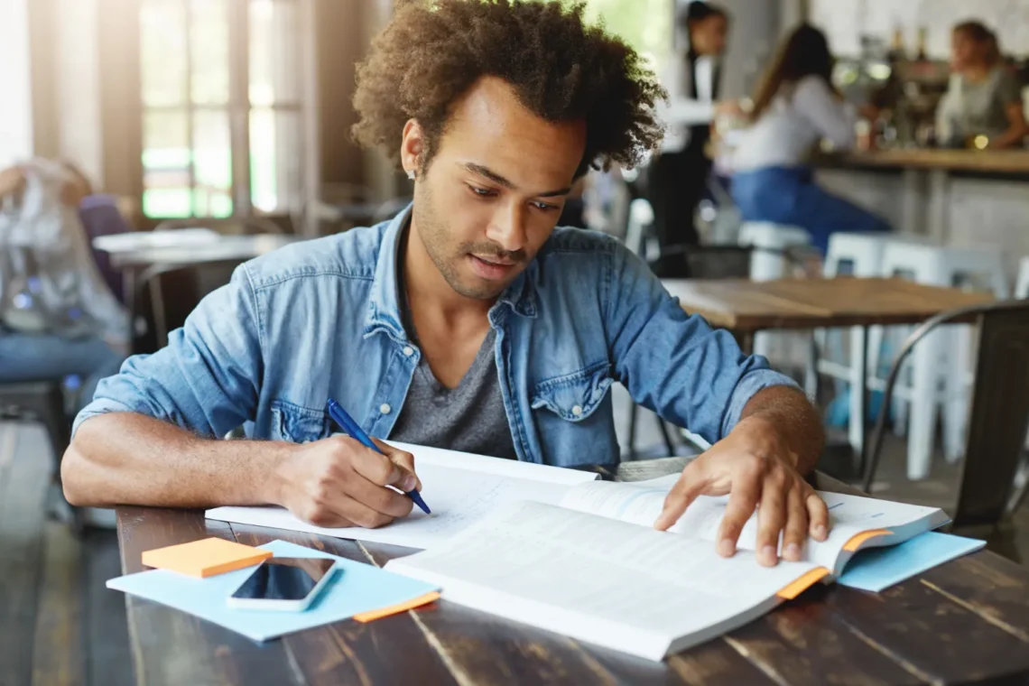 Homem estudando em um café, focado na preparação para o concurso da CAESB