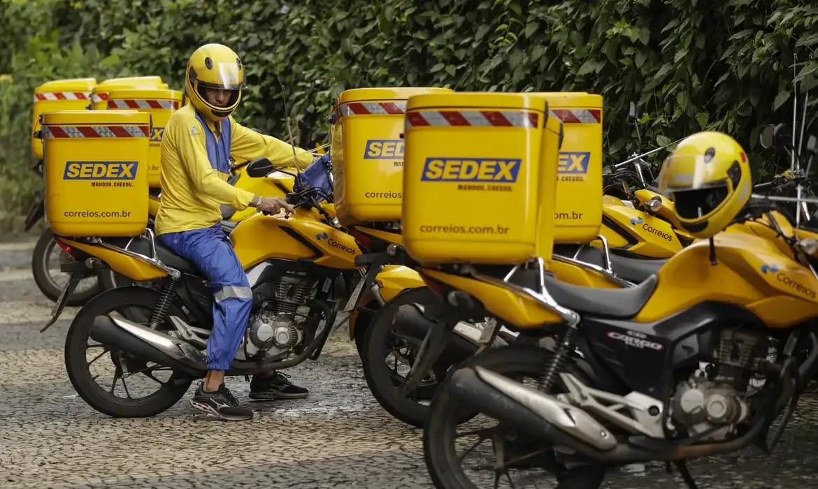 Motociclista dos Correios com uniforme amarelo, simbolizando carreiras e cargos nos Correios.