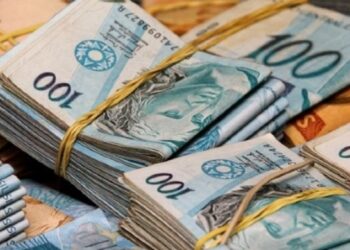 Foto de pilhas de dinheiro, com destaque para notas de 100 reais, ilustrando a alta remuneração de alguns servidores públicos no Brasil.