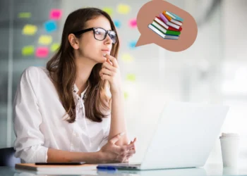 Mulher pensando enquanto trabalha em computador, simbolizando o equilíbrio entre estudo e trabalho.