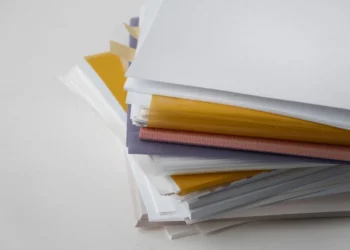 Pilha de papéis e pastas organizadas sobre uma mesa