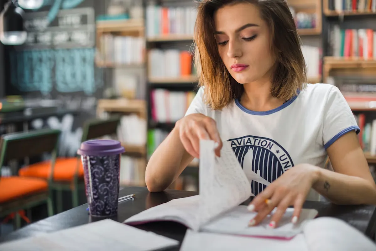 Pessoa estudando e folheando caderno, focada nos estudos para concurso técnico.