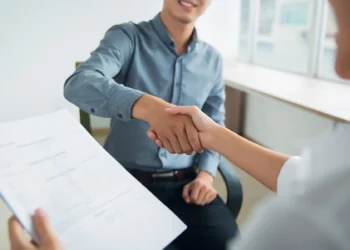 Mãos apertando-se em um aperto de mão, simbolizando a conclusão do processo seletivo.