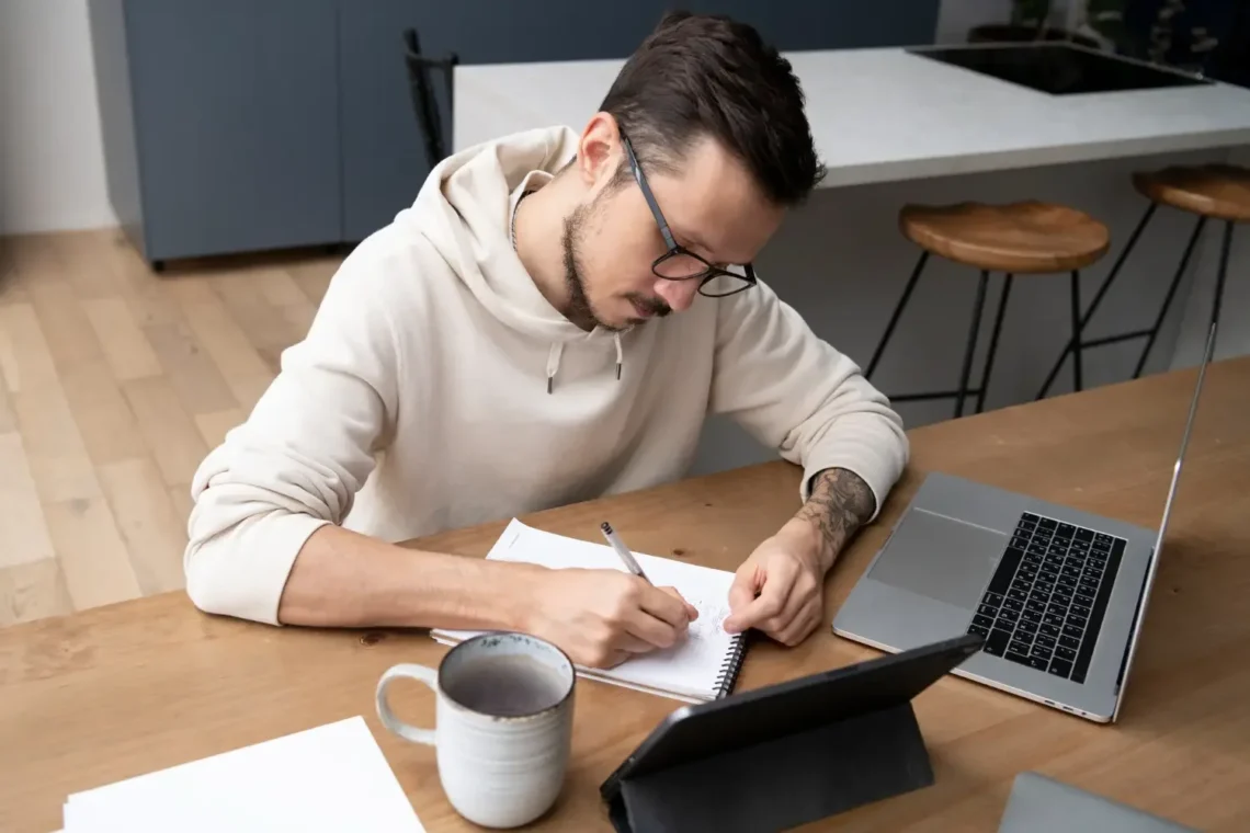 Homem estudando em sua mesa com computador e café, simbolizando a preparação para o concurso da Sefaz PI