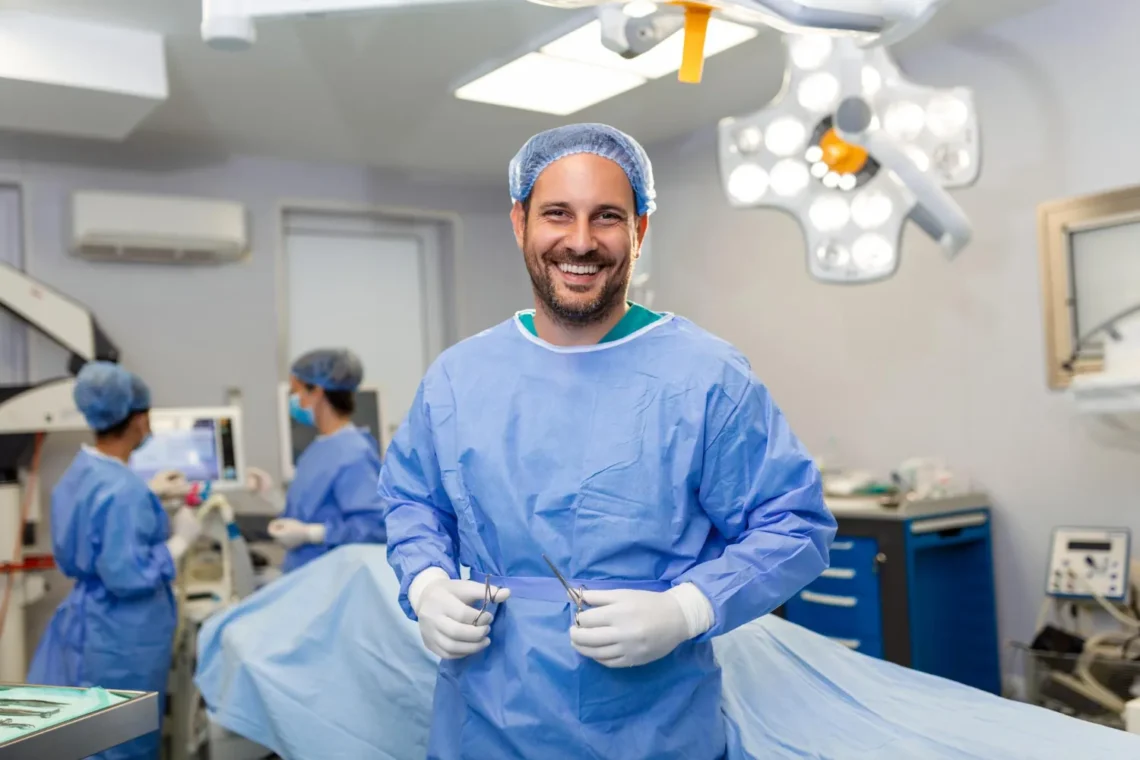 Cirurgião dentista sorrindo em centro cirúrgico, pronto para atendimento odontológico