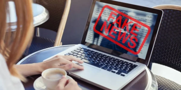 Pessoa verificando informações em um laptop com alerta de 'Fake News' sobre o CNU 2025