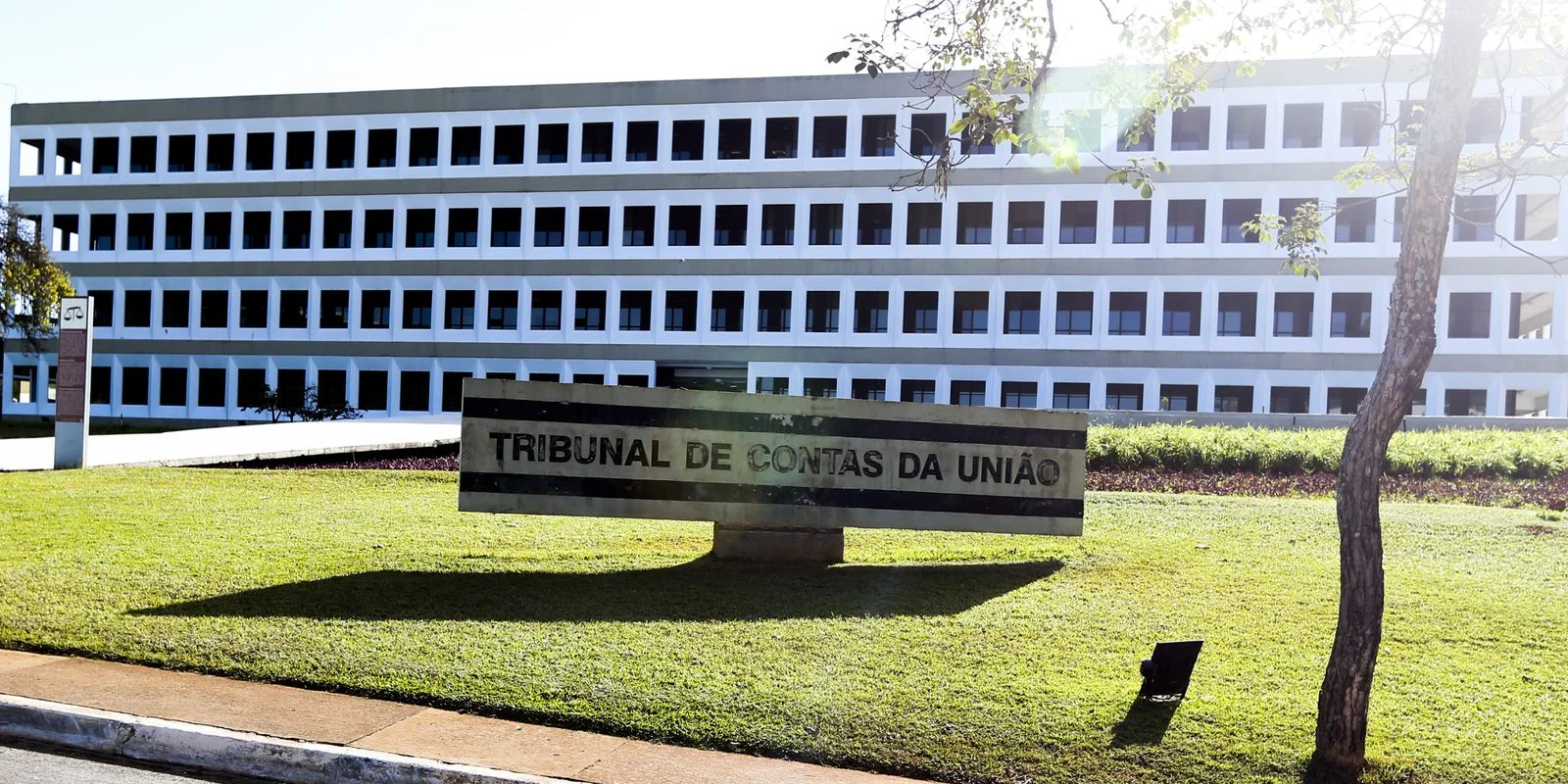 Fachada do Tribunal de Contas da União (TCU) com placa em destaque.