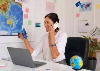 Agente de viagens ao telefone planejando uma viagem com cliente usando notebook e cartão.