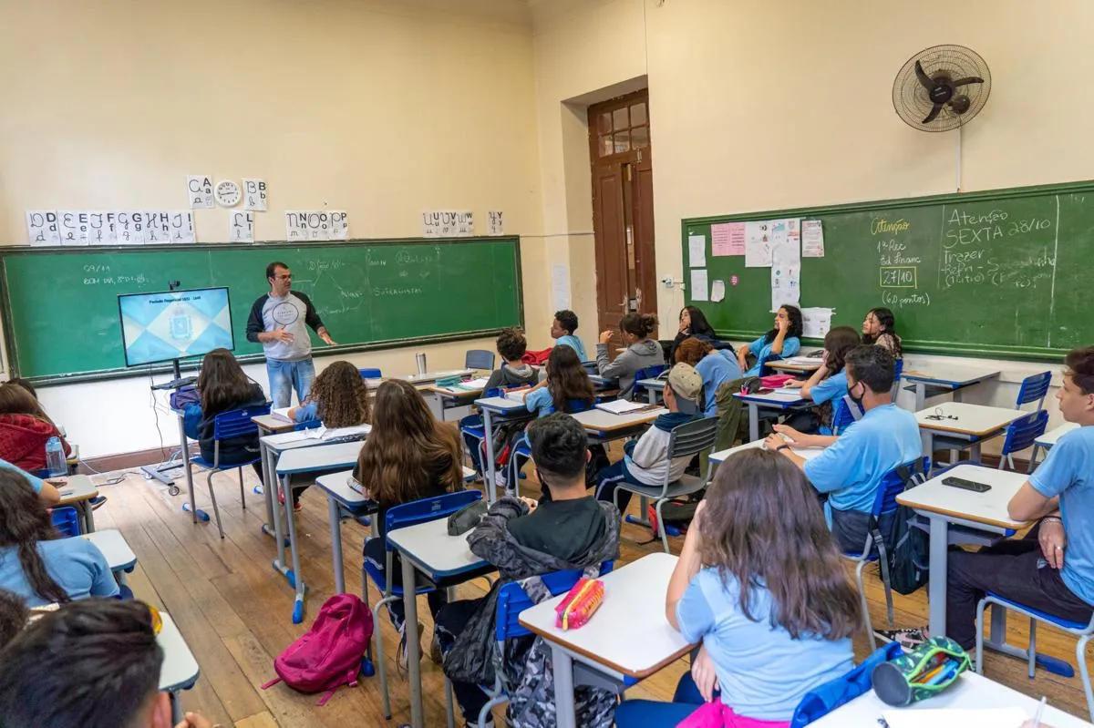 Professor explicando conteúdo para alunos em sala de aula.