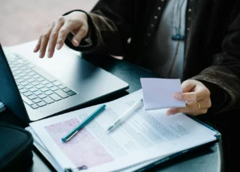 Pessoa estudando com laptop e anotações, ilustrando o planejamento de um cronograma de estudos.