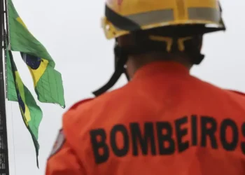 Bombeiro em frente à bandeira do Brasil, simbolizando o Concurso Bombeiros RS 2025