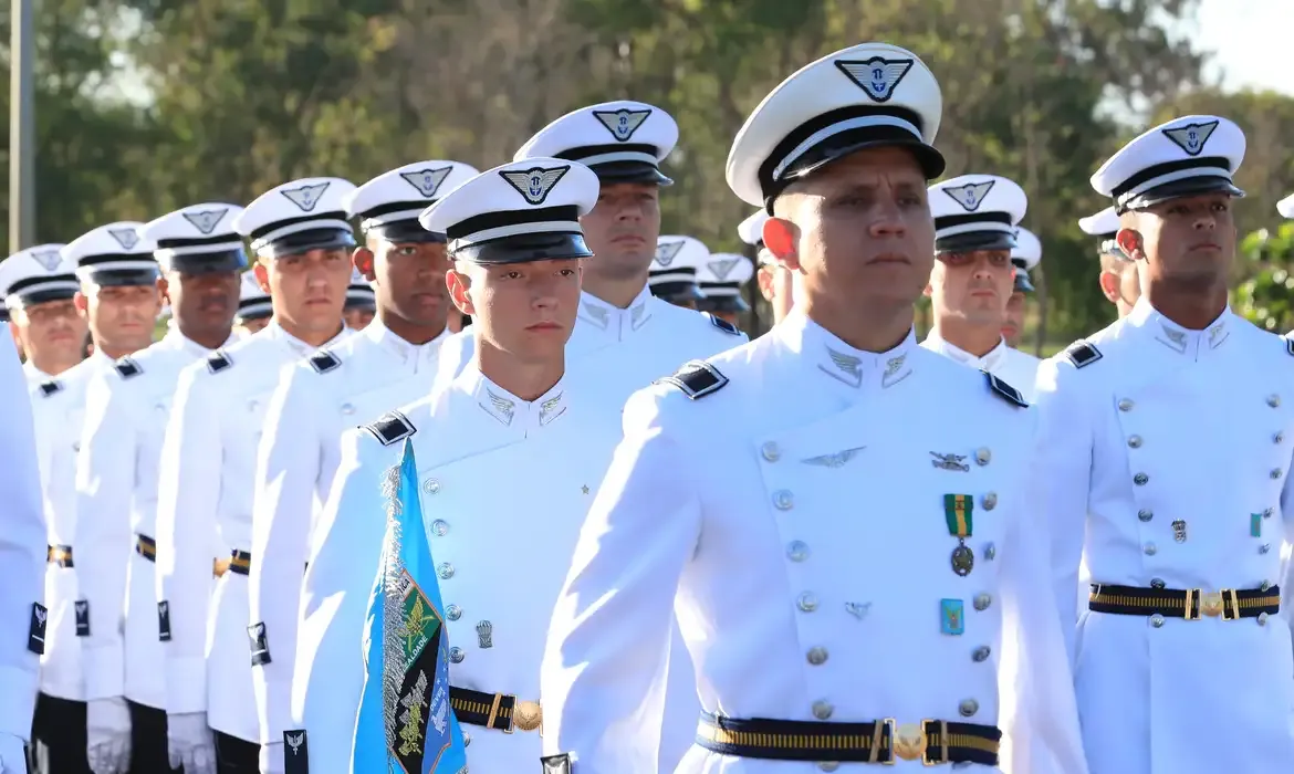 Cadetes da Aeronáutica em cerimônia de formatura, marchando com uniformes brancos