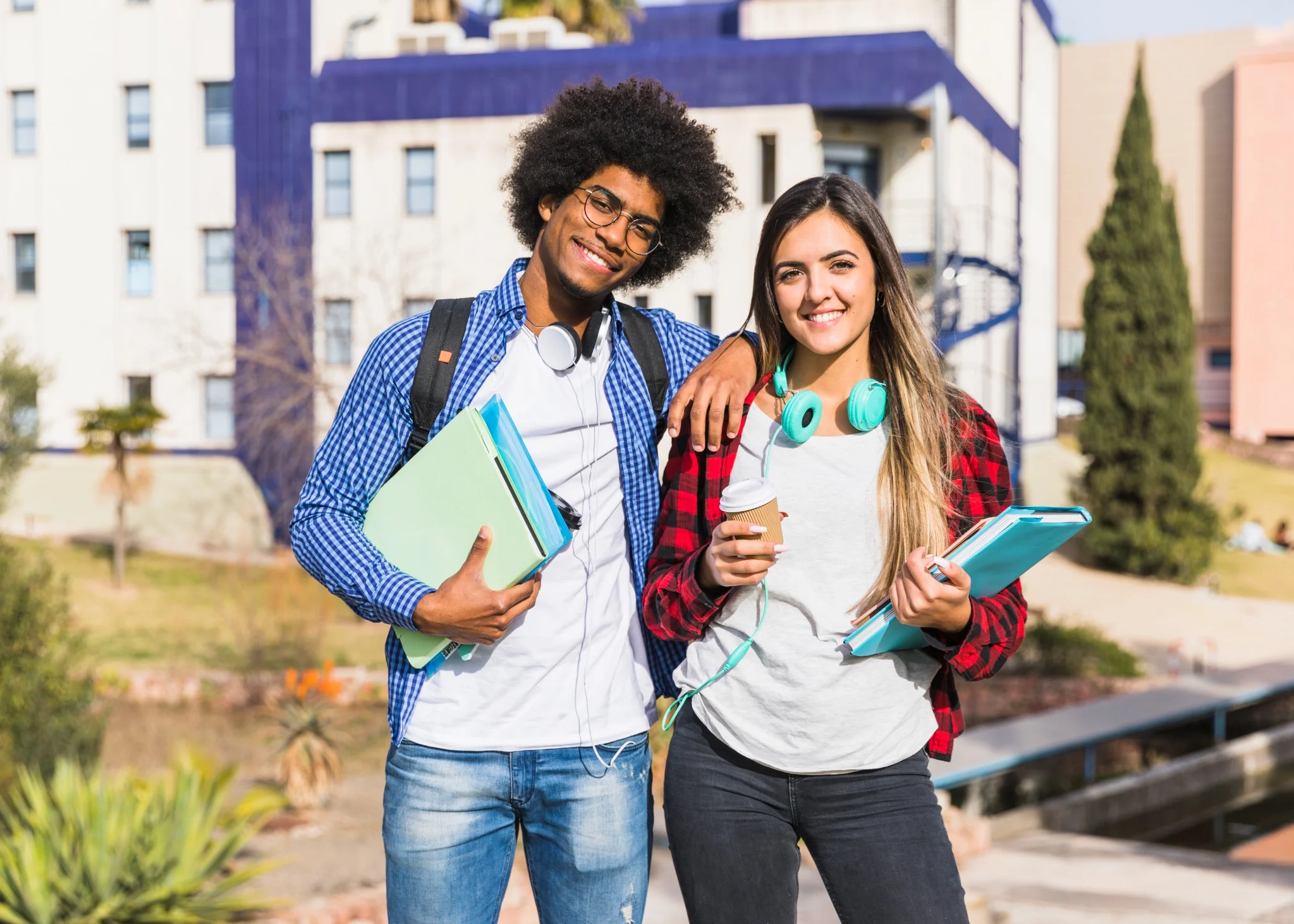 Casal sorridente posando em frente a um prédio universitário, simbolizando estudantes se preparando para o Encceja.