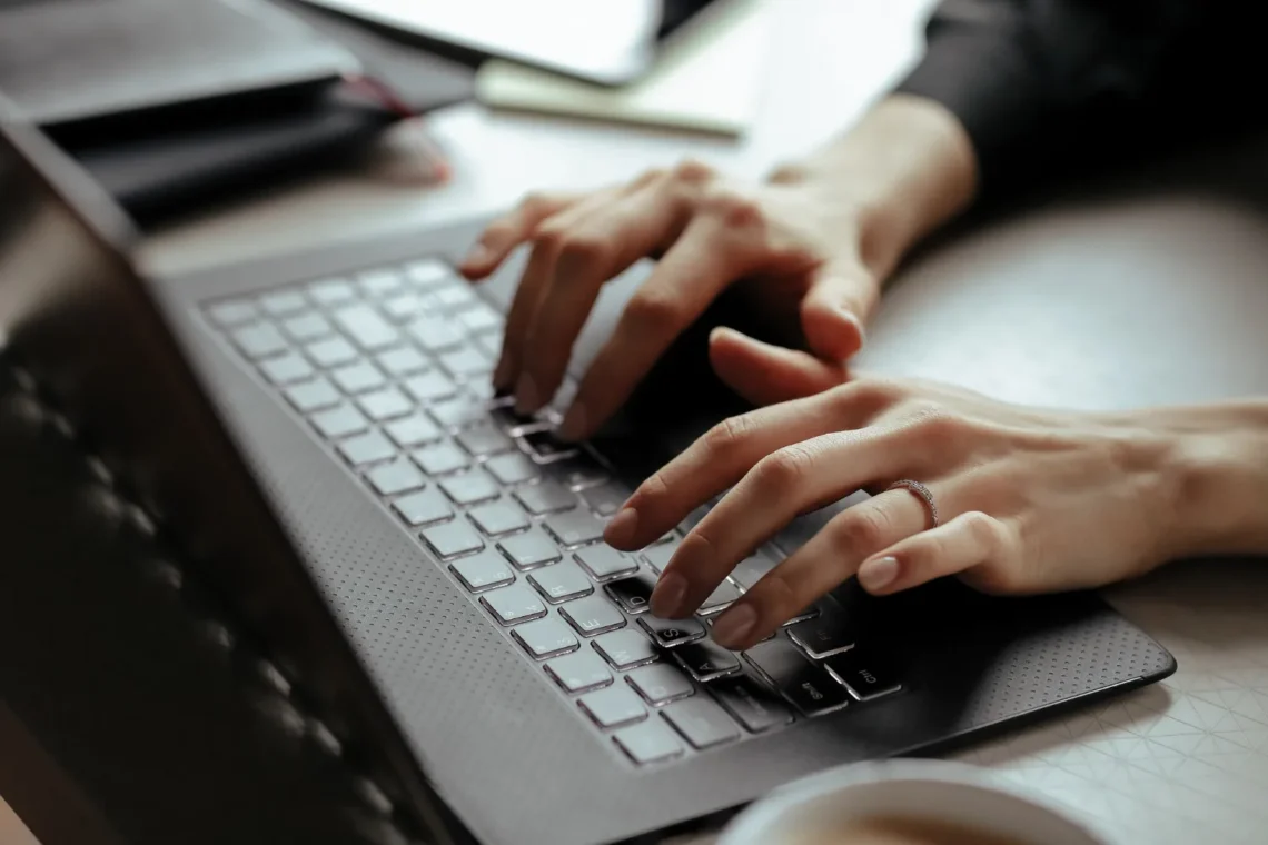 Mãos digitando em um notebook durante o processo de inscrição online