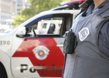 Policial militar com colete à prova de balas e câmera corporal, destacando segurança no trabalho