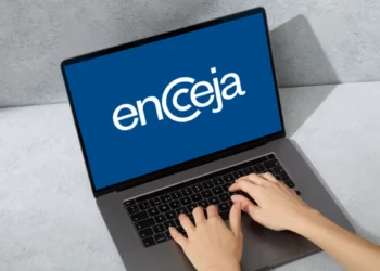 Pessoa digitando no computador com a tela exibindo o logo do Encceja.