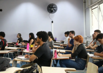 Estudantes concentrados durante aula em sala de aula com ambiente acadêmico.