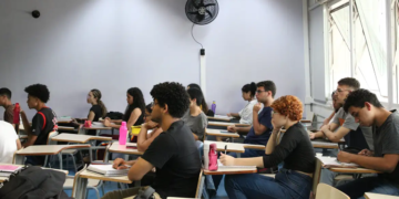 Estudantes concentrados durante aula em sala de aula com ambiente acadêmico.