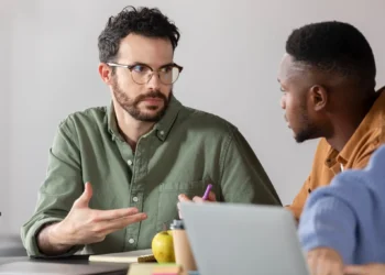 Dois homens discutindo durante uma sessão de estudos em um ambiente de trabalho.