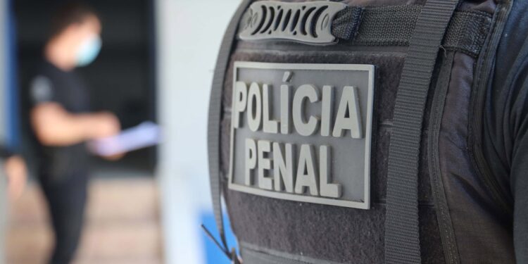 Detalhe do colete tático com identificação "Polícia Penal".