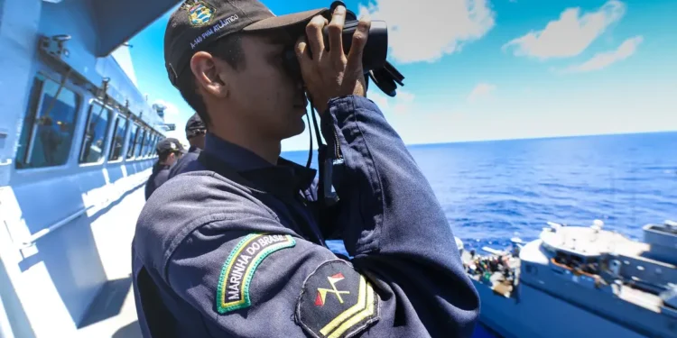 Militar da Marinha do Brasil observando o horizonte com binóculo durante operação no mar