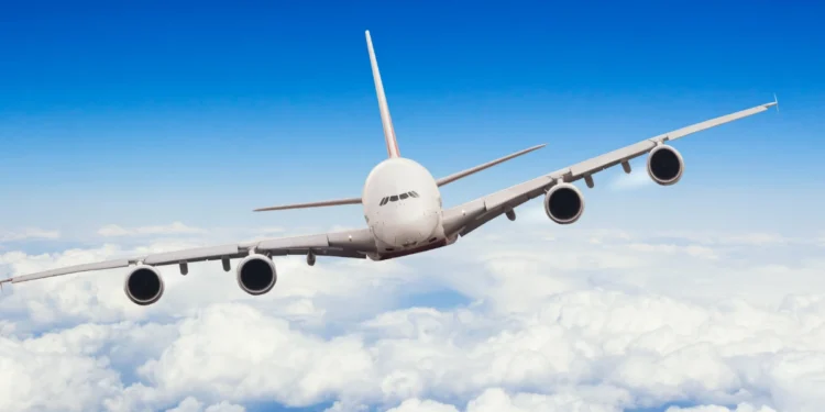 Avião Airbus voando sobre nuvens com céu azul claro.