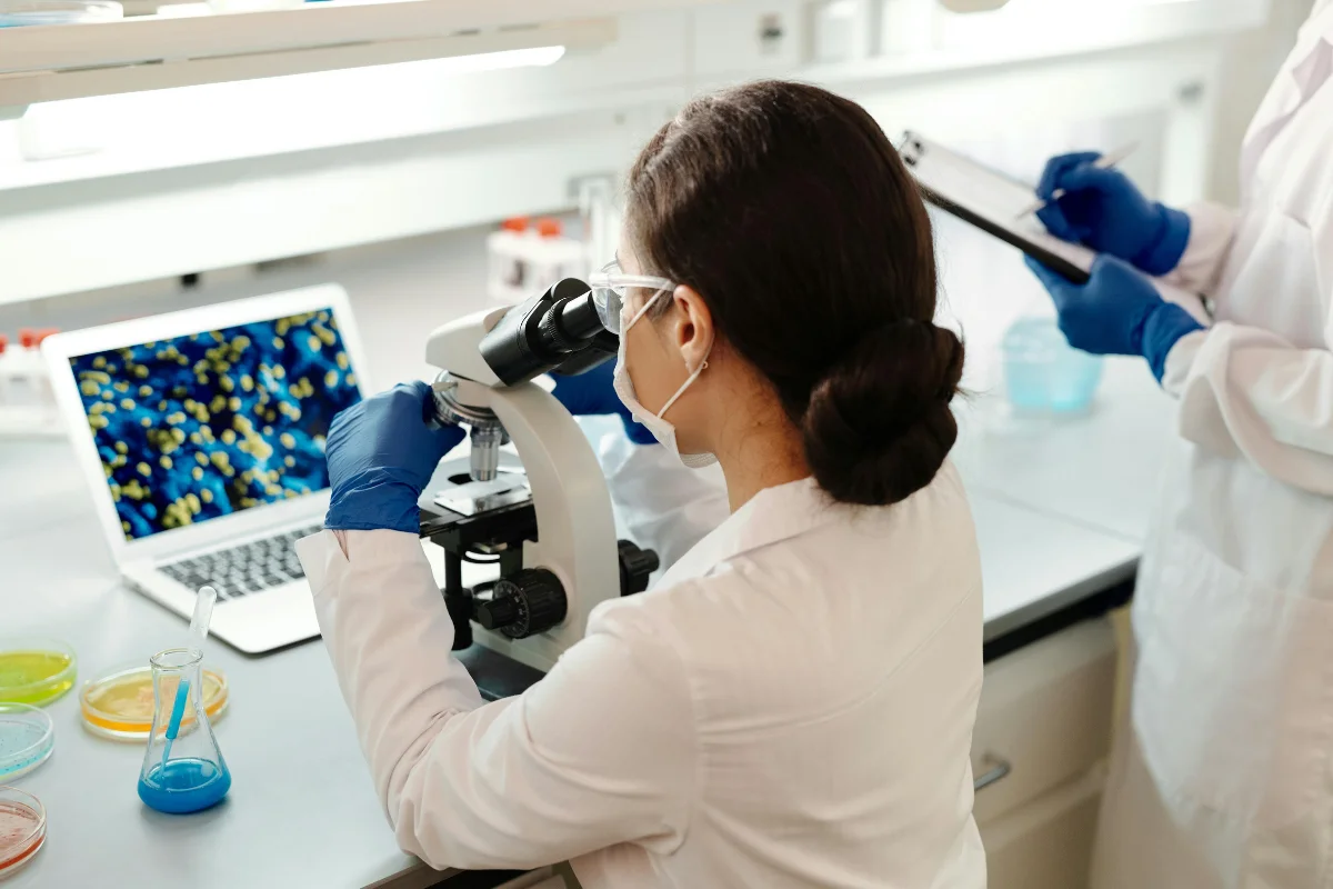 Pesquisadora analisando amostras microscópicas em laboratório.