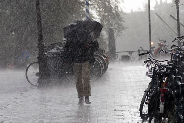 Chuva intensa durante caminhada na cidade Pessoa caminhando na chuva forte com guarda-chuva preto aberto