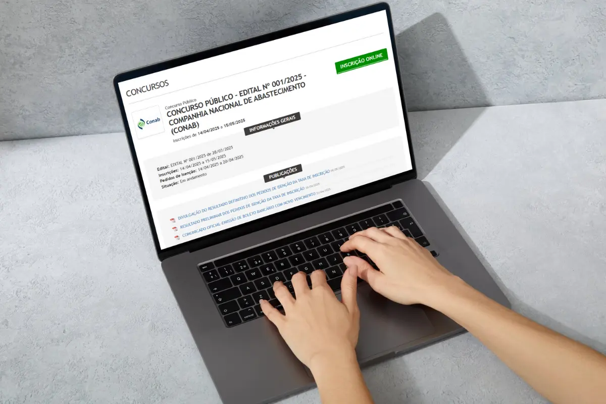 Pessoa digitando em um laptop com o site de inscrição do concurso da CONAB aberto na tela.