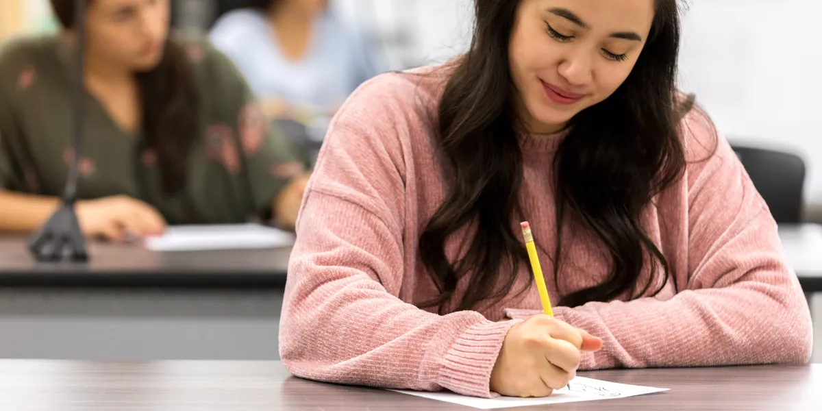 Estudante concentrada preenchendo informações, representando o foco necessário para concursos públicos.