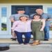 Desafio visual com uma família sorridente em frente à porta da casa, com dois adultos e dois jovens reunidos na entrada.
