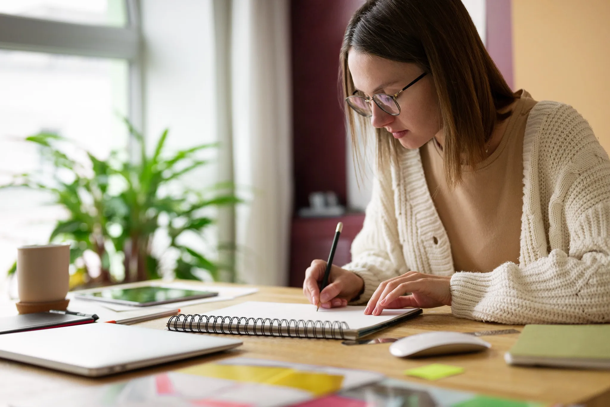 Mulher concentrada escrevendo em caderno durante planejamento de estudos em ambiente tranquilo,