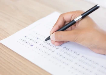 Pessoa preenchendo gabarito da prova.