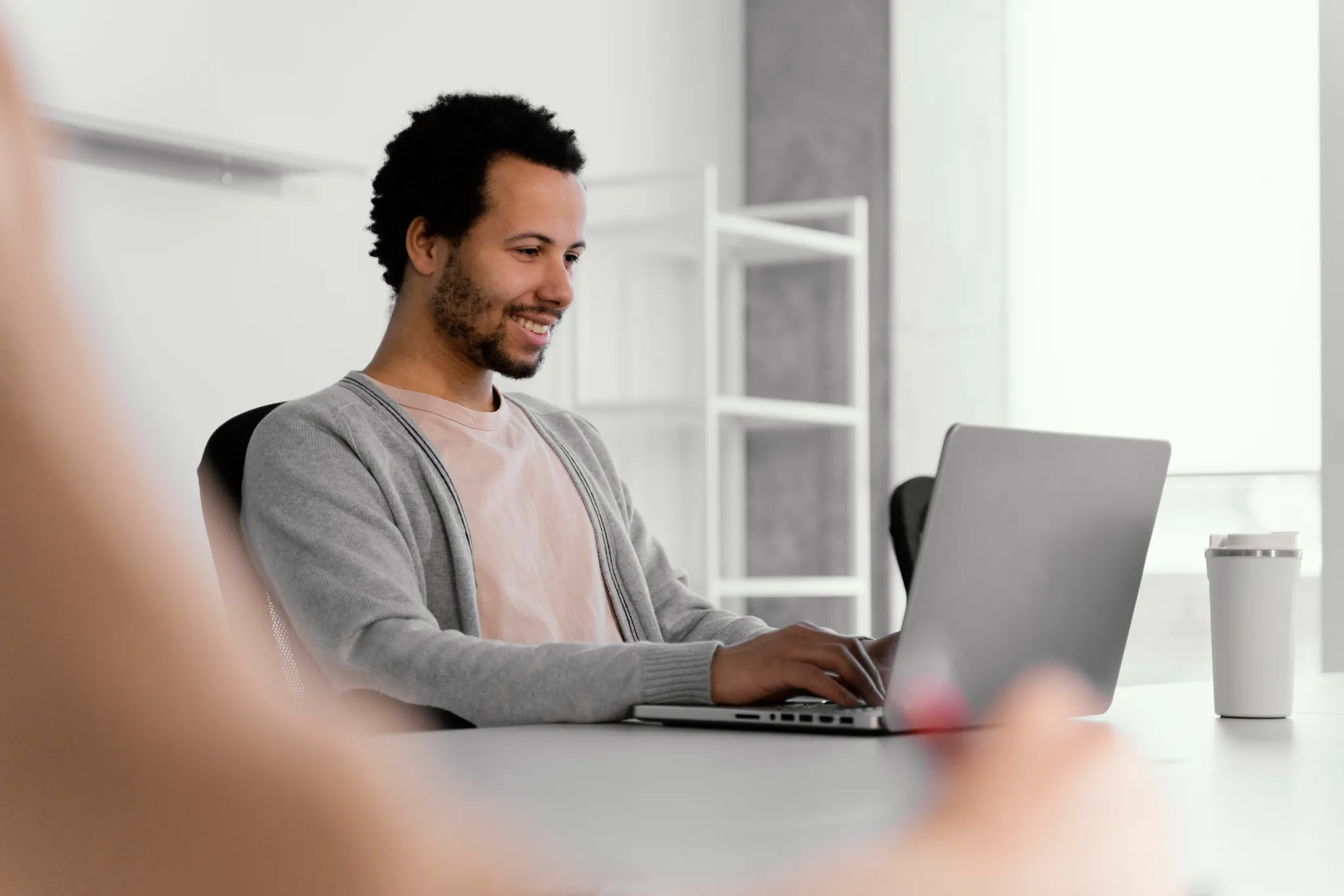 Homem digitando em notebook em ambiente corporativo.