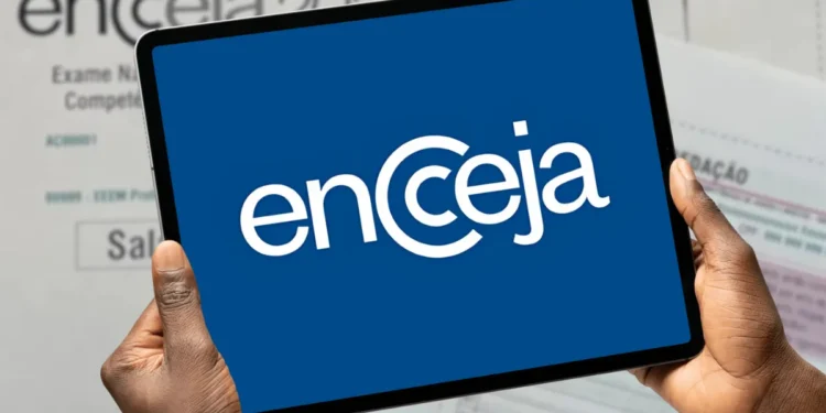 Logo do Encceja exibido em um tablet segurado por mãos, com documentos do exame ao fundo.