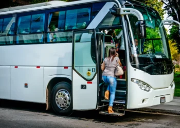 Mulher entrando em ônibus branco urbano