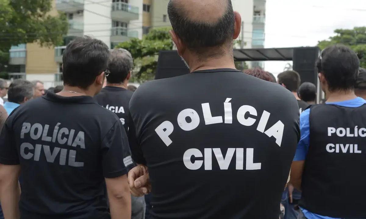 Grupo de policiais civis de costas durante um evento ao ar livre na cidade.