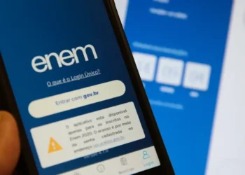 Tela de login do aplicativo ENEM exibida em um smartphone com fundo desfocado mostrando contagem regressiva do exame.