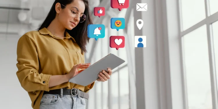 Mulher usando tablet com ícones de redes sociais flutuando ao redor, representando marketing digital e engajamento online